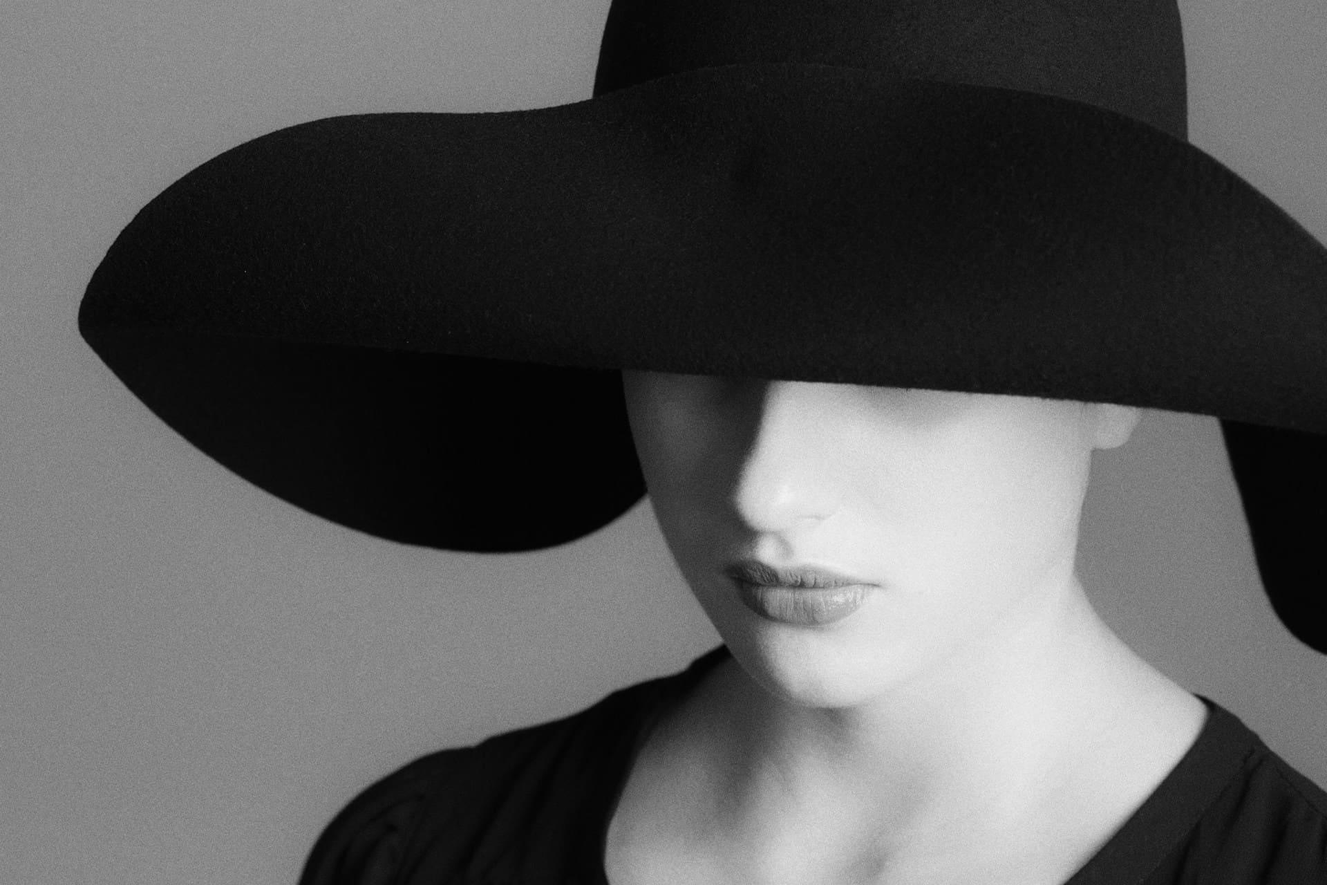 A woman wearing a black hat with large ears, smiling and looking directly at the camera.
