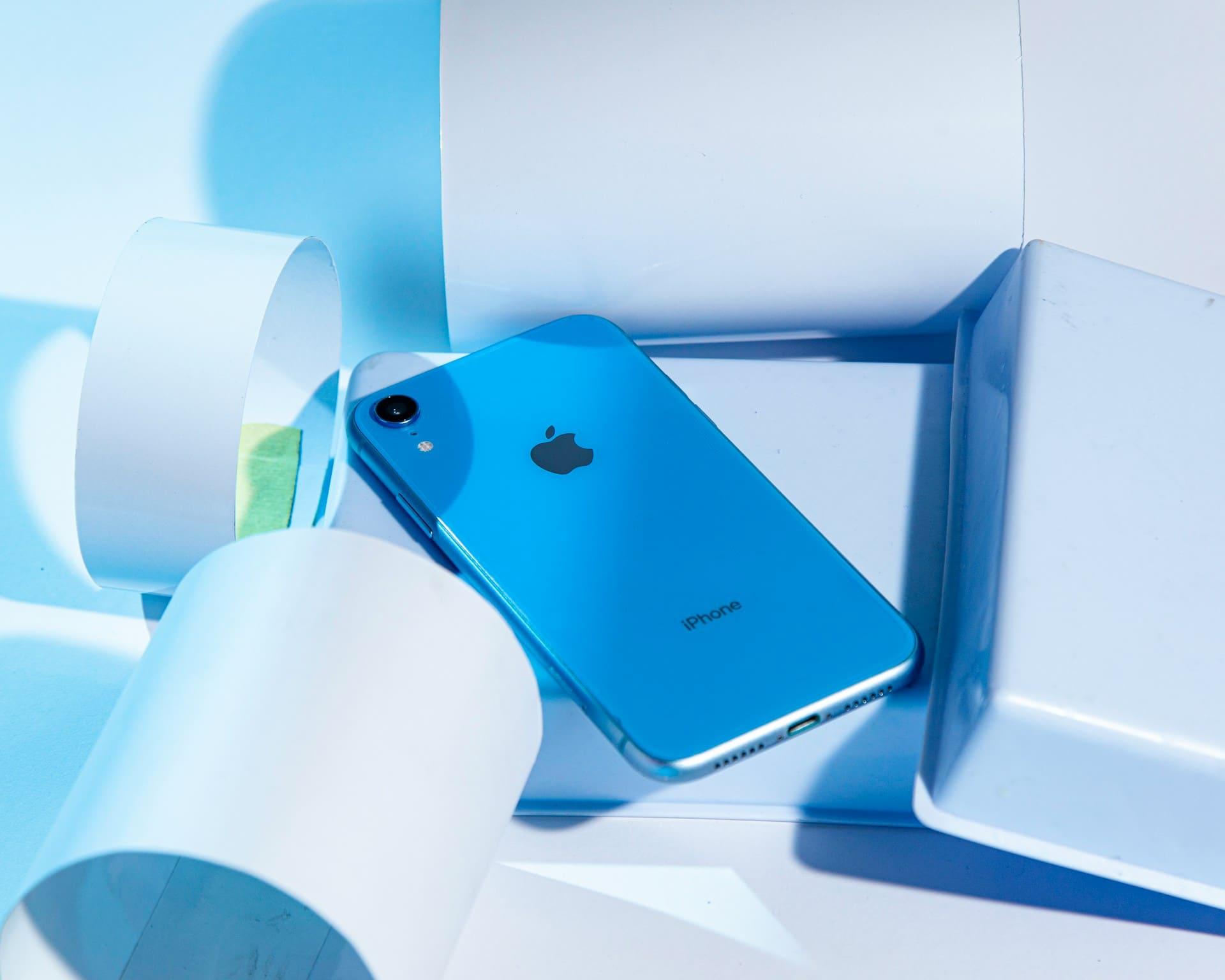 iPhone resting on a blue box, showcasing a modern device against a vibrant background.