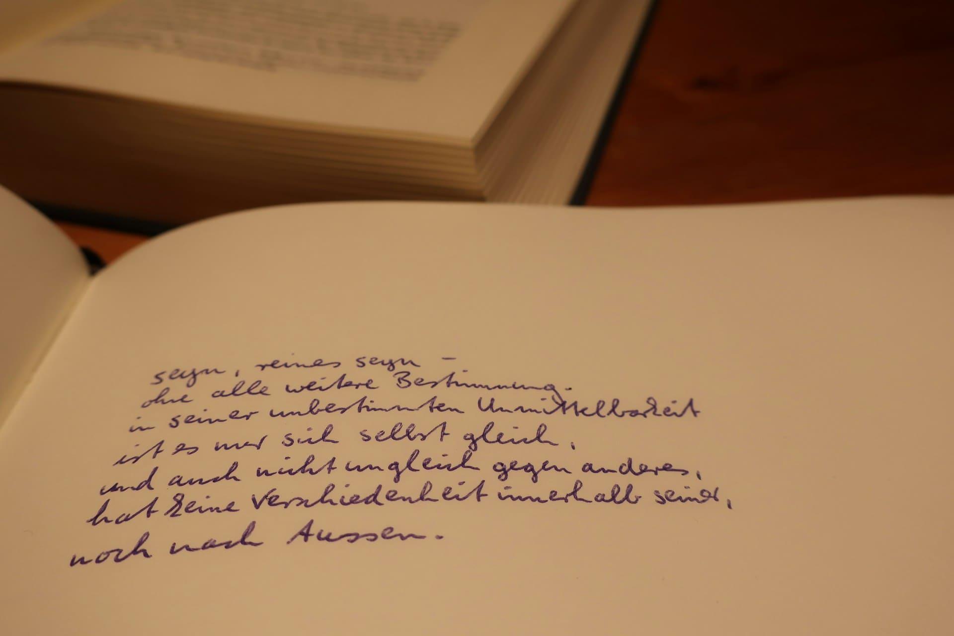 A book with handwritten notes and text visible on its pages, resting on a wooden surface.