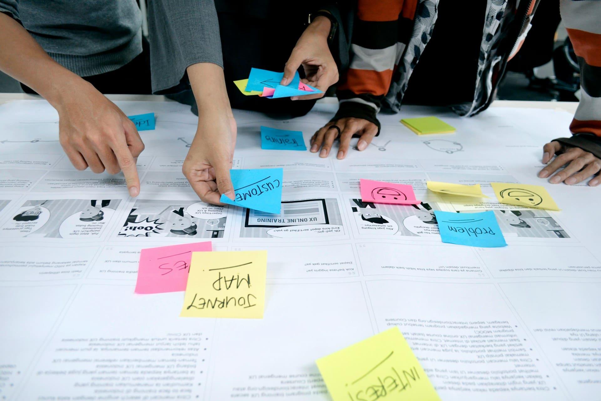 A diverse group of people collaborating on a project, surrounded by colorful sticky notes on a table and wall.