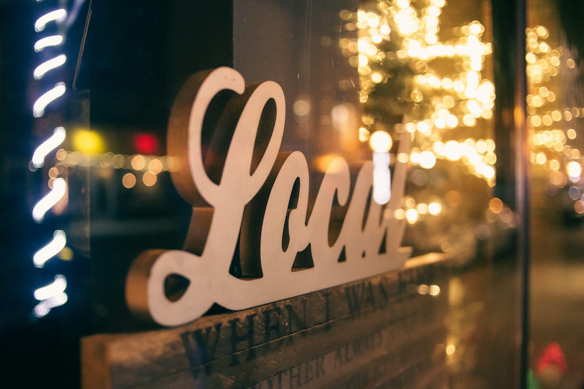 'Local' sign featuring the name in bold letters against a vibrant background.