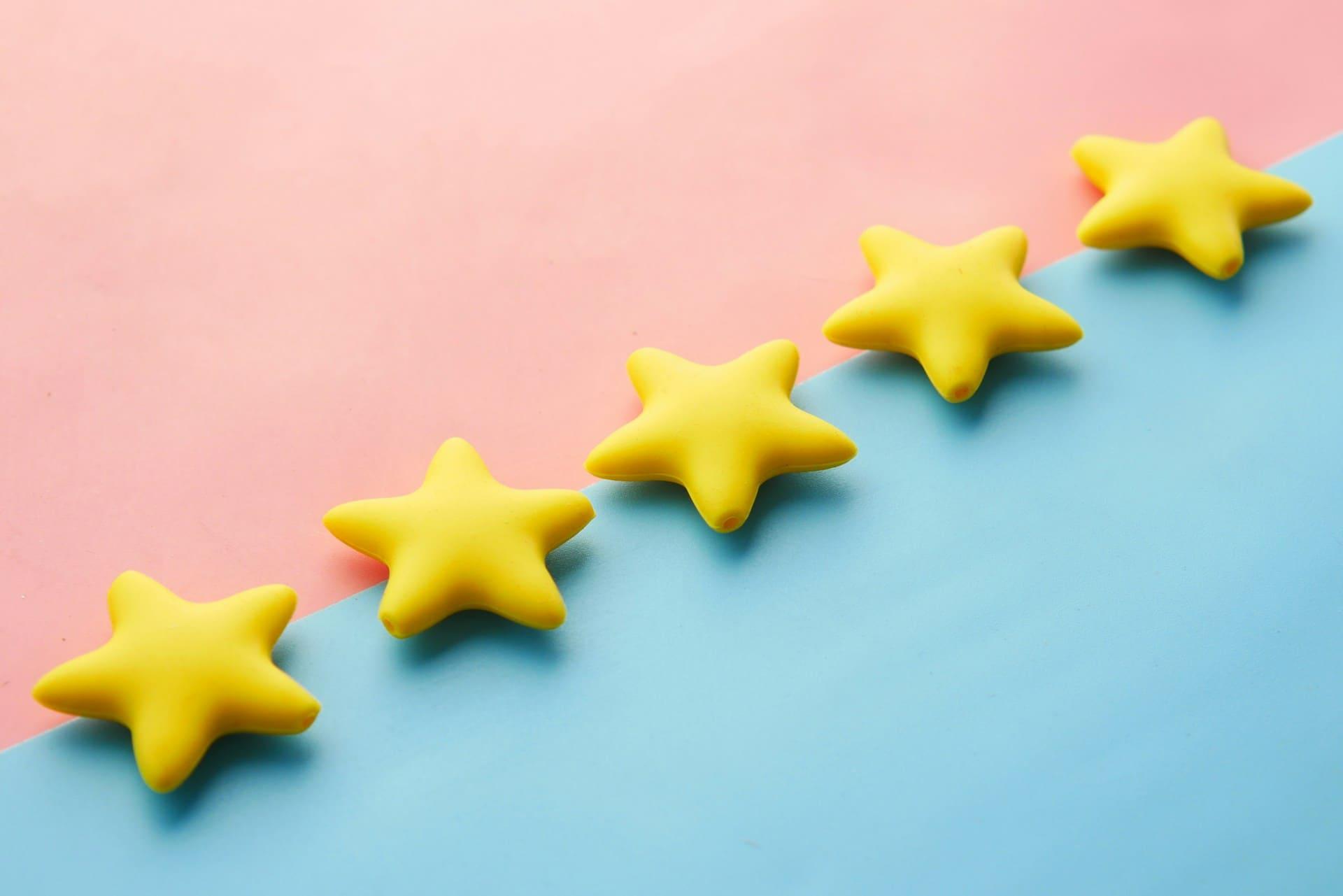 Five yellow star-shaped toys arranged on a vibrant blue and pink background.